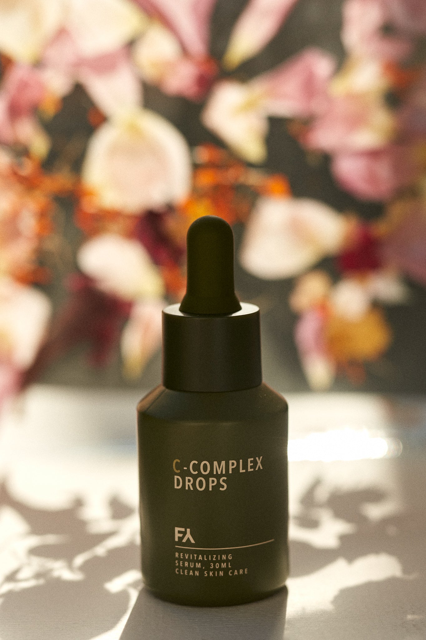 Campaign shot of the C-Complex Drops Revitalizing Serum by Fields of Yarrow with flowers in the background
