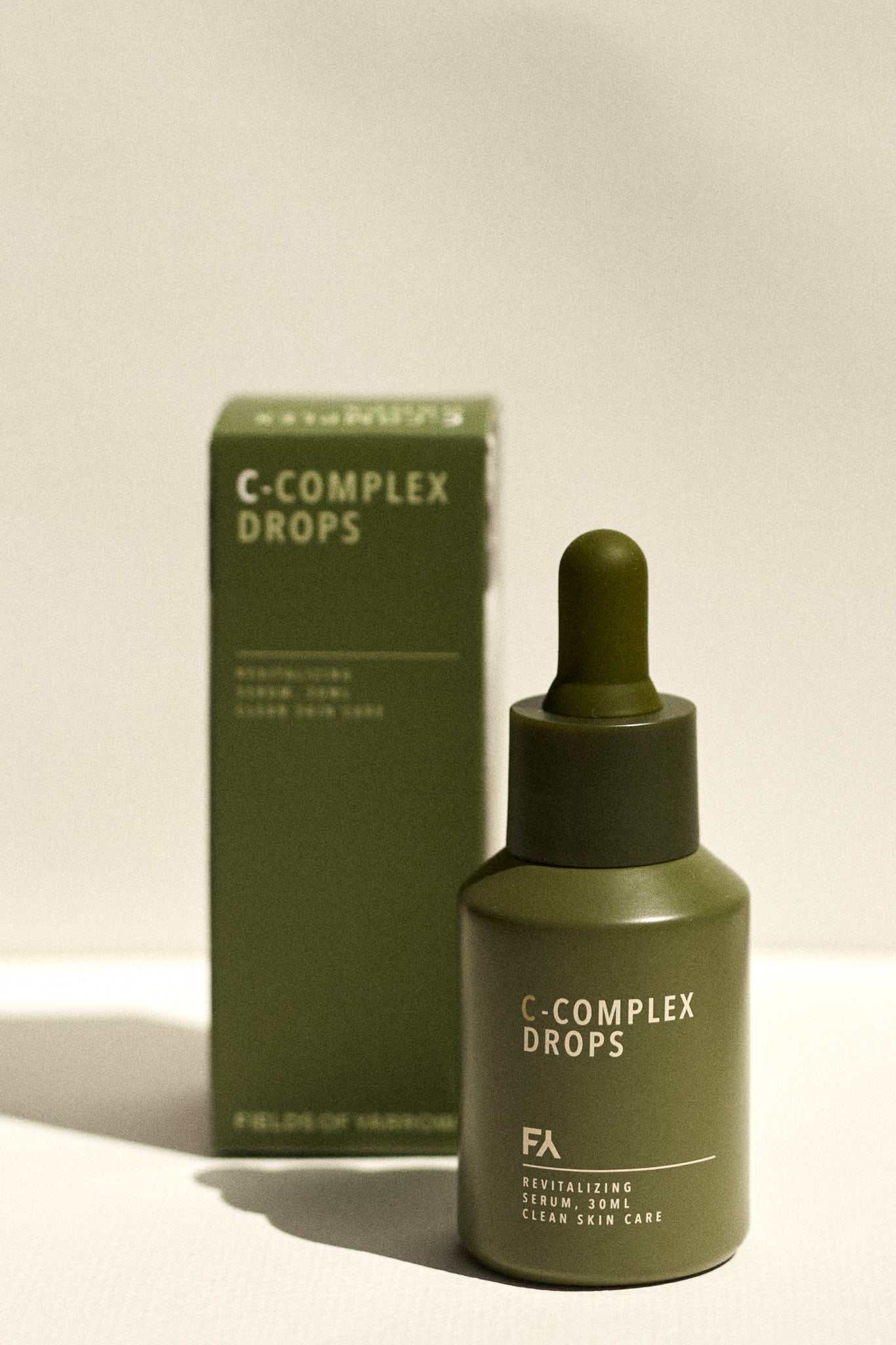 Campaign shot of the C-Complex Drops Revitalizing Serum by Fields of Yarrow next to its packaging