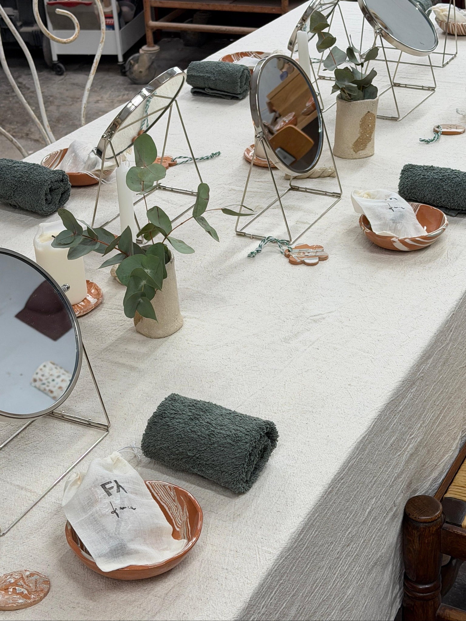 Table with decorative items including mirrors, plants, and towels in a room setting.